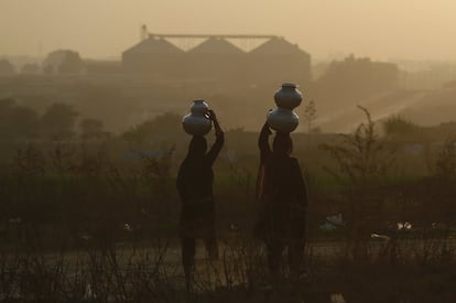 Unas mujeres nómadas pakistaníes llevan bidones de agua a sus casas, a las afueras de Islamabad (Pakistán).