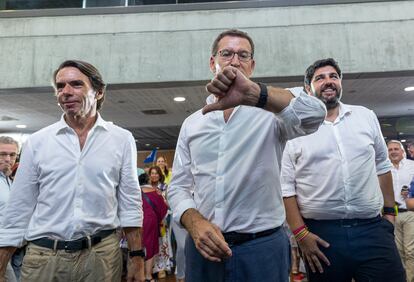 El líder del PP, Alberto Núñez Feijóo, mira su reloj al término del mitin en Murcia, junto a Aznar y al presidente en funciones de la comunidad, Fernando López Miras.