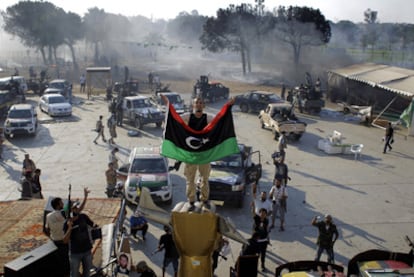 Un combatiente rebelde exhibe la antigua bandera libia en Bab el Azizia, el fortín de Gadafi.