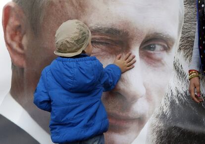 Un niño acaricia un póster que representa al presidente ruso Vladimir Putin en San Petersburgo, el 1 de mayo de 2015.