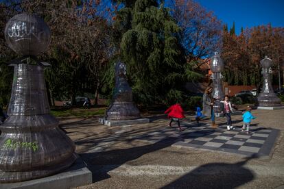 Una madre juega con sus hijos encima de un tablero de ajedrez gigante en un parque en Madrid este sábado.