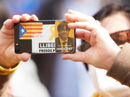 Una mujer toma una foto durante una manifestación, en la que exhibe una pegatina del expresidente Carles Puigdemont