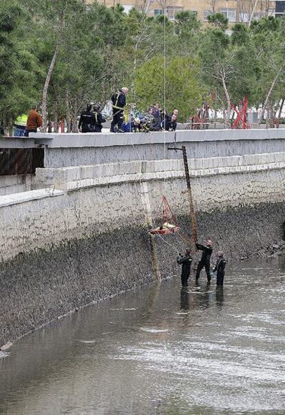 Los bomberos suben el cuerpo, tapado con una manta térmica, desde la orilla del río Manzanares.