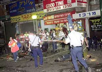 Policías y miembros de los servicios de socorro, en el lugar del atentado suicida, anoche en Tel Aviv.