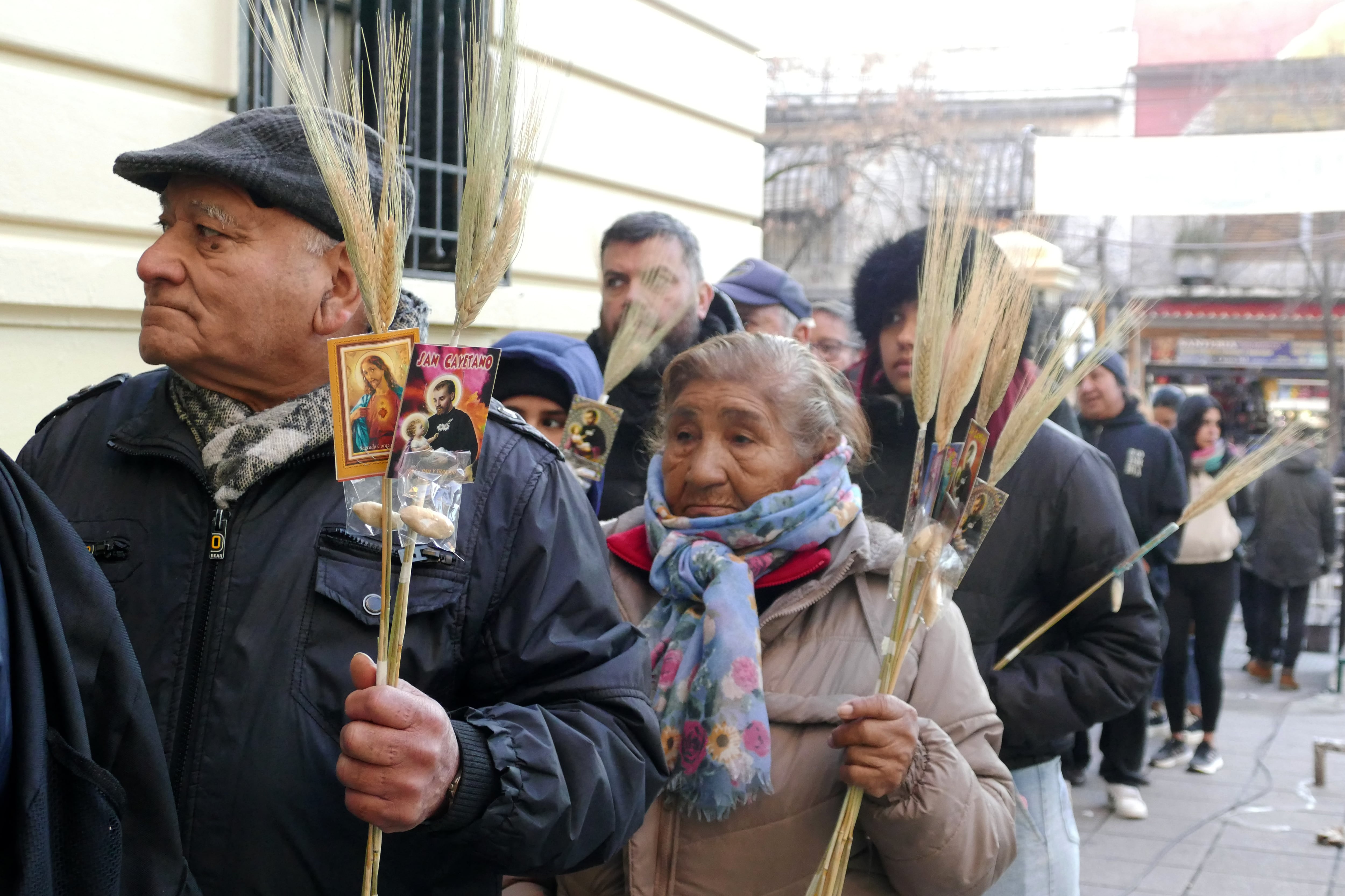 Personas esperan a la entrada de la iglesia en el barrio Liniers con imágenes de San Cayetano.
