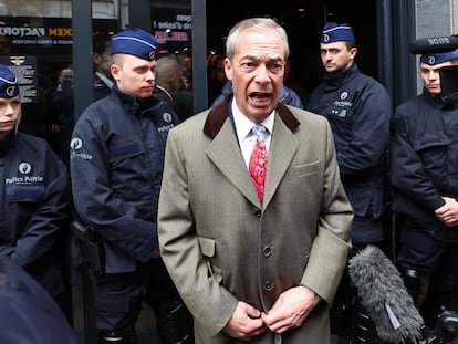 El político británico Nigel Farage habla con los medios de comunicación en la puerta del lugar donde se celebra la conferencia National Conservatism con la policía detrás, el 16 de abril en Bruselas.