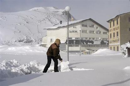 Una mujer quita nieve con una pala a la entrada de su tienda, hoy junto al paso fronterizo del Portalet.