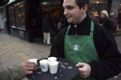 Un trabajador de un establecimiento Starbucks reparte chocolate caliente entre los viandantes en la calle Oxford Street, Londres, Reino Unido. EFE/Archivo