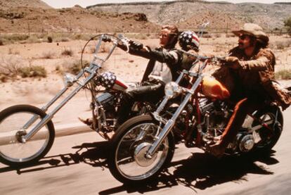 Peter Fonda (izquierda) y Dennis Hopper, en un momento de la película <i>Easy rider</i>.
Hopper, a la izquierda, junto a Sharon Farrell y Linda Manz en <i>Caído del cielo.</i>