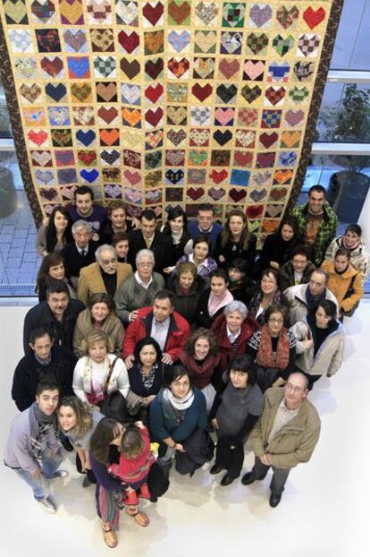 Miembros de la Asociación 11-M, delante del <i>patchwork</i> <i>Trazos y puntadas para el recuerdo.</i>