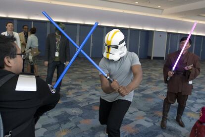 Uno de los protagonistas de la nueva película 'Star Wars: El despertar de la fuerza', el actor John Boyega, se disfrazó con un casco de soldado imperial para poder interactuar con los asistentes a la convención. En la imagen se lo ve luchando contra uno con una espada laser.