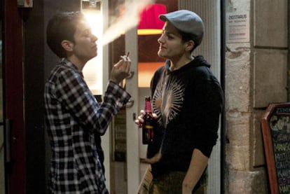 Una joven fuma en la calle mientras otra bebe una cerveza, el viernes por la noche en el barrio del Raval, en Barcelona.