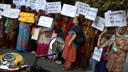 Un polic&iacute;a vigila desde su motocicleta una protesta de mujeres en Nueva Delhi.