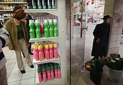 Una mujer israelí mira artículos en un supermercado. Fuera de la tienda, un judío ultraortodoxo.