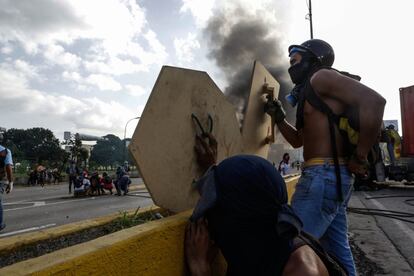 Dos jóvenes se protegen con dos maderas durante los enfrentamientos con los militares.