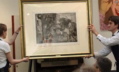 Dos trabajadores sujetan el grabado <i>La minotauromaquia</i> de Pablo Picasso, expuesto en la casa de subastas Sotheby's en Londres.