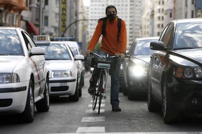 Un ciclista, con m&aacute;scara para protegerse de la contaminaci&oacute;n que producen los coches, circula por Madrid. / Samuel S&aacute;nchez