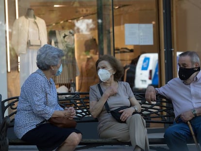 Três pessoas com máscaras conversam sentadas num banco, em Madri, na quarta-feira passada.