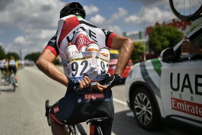 El ciclista colombiano, Darwin Atapuma, se coloca en el maillot botellas de agua para sus compañeros de equipo en la sexta etapa de la carrera francesa desde Brest hasta el Muro de Bretaña, el 12 de julio de 2018.