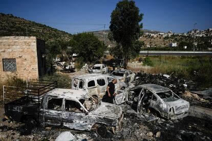 A Palestinian man inspects scorched cars, including some junked for spare parts, in the West Bank village of A Laban al-Sharkiyeh