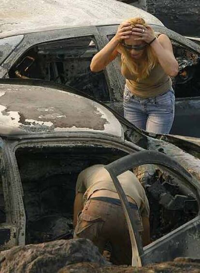 Dos personas observan los daños causados por el fuego en su coche en Artemida, cerca de Zaharo.