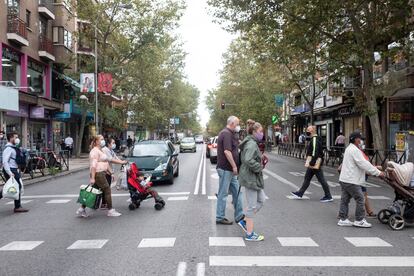 Peatones cruzan un paso de cebra en la calle Alcalá, cerca de la boca de Metro de Pueblo Nuevo. A la derecha la zona verde, a la izquierda la zona roja.