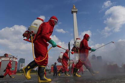 Un grupo de bomberos desinfecta la zona del Monumento Nacional para prevenir la propagación del coronavirus, en Yakarta (Indonesia)