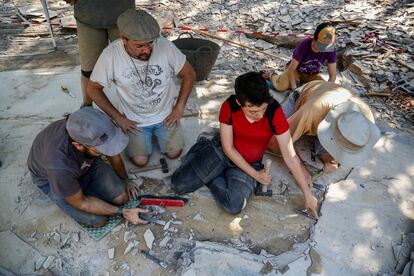 El paleontólogo Jesús Marugan (de rodillas) observa un resto fósil en una de las zonas de estudio del yacimiento de Las Hoyas.