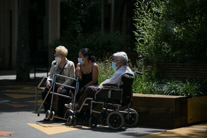 Dos ancianos junto a una joven toman el aire en el barrio de Sant Antoni de Barcelona.