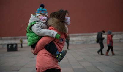 Una mujer y un bebé con máscaras a los pies de la Ciudad Prohibida de Pekín.
