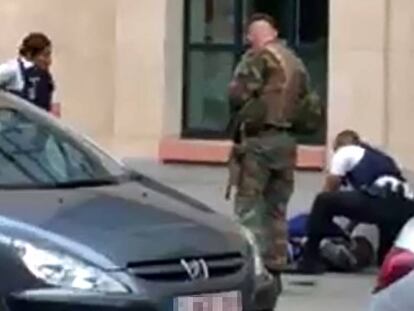 Polic&iacute;as y un soldado rodean a un hombre tendido en el suelo en el lugar donde dos soldados han sido atacados en el centro de Bruselas. 