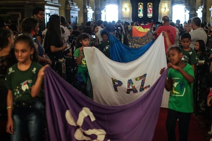 Momento final da celebração religiosa, com crianças levando bandeiras em direção ao altar da igreja.