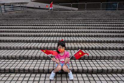 Una niña ondea banderas de la República Popular China en el Puerto Victoria, en Hong Kong, este viernes. El 25 aniversario del retorno de Hong Kong a la soberanía china, que se conmemora hoy, primero de julio, marca la mitad del camino desde su pasado como colonia británica a su plena integración en China, prevista para 2047, entre la continua preocupación de gran parte de la población sobre el futuro de sus libertades.
