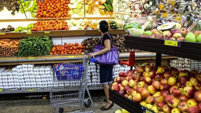 Una mujer compra verduras en un supermercado.