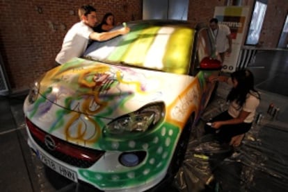 Intervención artística de voluntarios sobre un coche expuesto en la feria.
