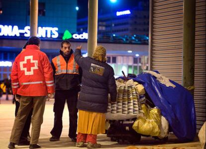 Trabajadores sociales y voluntarios de la Cruz Roja hablan con una sin techo para facilitarle un sitio donde dormir debido a la ola de frío.