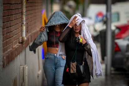 Dos mujeres se protegen de la lluvia en el distrito de Usera, en el sur de Madrid.