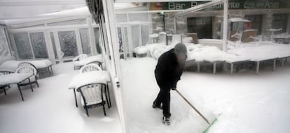 Un trabajador retira la nieve de la puerta de un bar en Navacerrada.