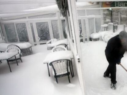 Un trabajador retira la nieve de la puerta de un bar en Navacerrada.