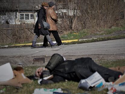 Dos mujeres pasan junto a un cadáver en Bucha (Ucrania), el 5 de abril.