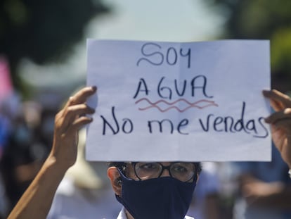 Una monja sostiene un cartel que dice "Soy agua, no me vendas" durante una marcha en El Salvador.