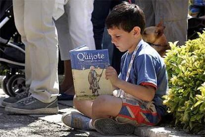 Un niño lee una versión ilustrada de <i>El Quijote</i> en el recinto de la Fira del Llibre de Valencia.