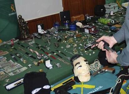 Un agente muestra, junto al material robado, la pistola del calibre 22 decomisada a los detenidos.