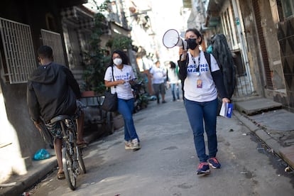 Voluntária usa megafone para convocar moradores do conjunto de favelas da Maré para se vacinarem contra a covid-19.