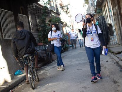 Voluntária usa megafone para convocar moradores do conjunto de favelas da Maré para se vacinarem contra a covid-19.