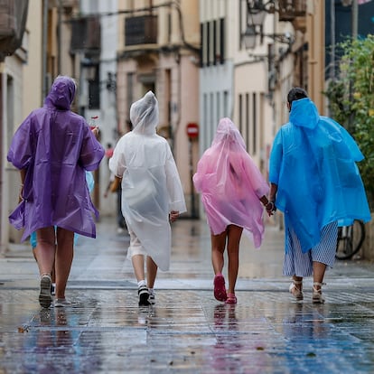 GRAFCVA2304. VALENCIA, 14/08/2024.- Varias personas caminan bajo la lluvia por una calle del centro de Valencia. La Aemet ha establecido el aviso naranja para este miércoles por tormentas con probable granizo y rachas muy fuertes de viento en toda la provincia de Alicante y en el sur de Valencia. EFE/Manuel Bruque
