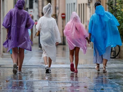 GRAFCVA2304. VALENCIA, 14/08/2024.- Varias personas caminan bajo la lluvia por una calle del centro de Valencia. La Aemet ha establecido el aviso naranja para este miércoles por tormentas con probable granizo y rachas muy fuertes de viento en toda la provincia de Alicante y en el sur de Valencia. EFE/Manuel Bruque