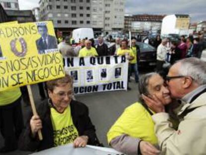 Una mujer porta una pancarta con las fotografías del presidente de la Xunta de Galicia, Alberto Núñez Feijoo, y el presidente de Novagalicia Banco, José María Castellano, durante una manifestación por las calles de Carballo (A Coruña). EFE/Archivo