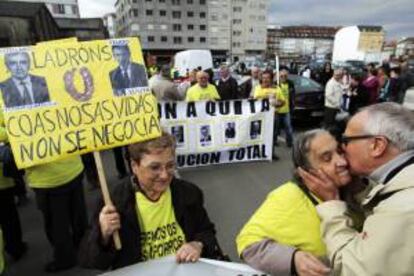 Una mujer porta una pancarta con las fotografías del presidente de la Xunta de Galicia, Alberto Núñez Feijoo, y el presidente de Novagalicia Banco, José María Castellano, durante una manifestación por las calles de Carballo (A Coruña). EFE/Archivo