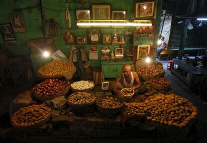 Un vendedor de patatas en su tienda de un mercado de verduras de Calcuta, India.